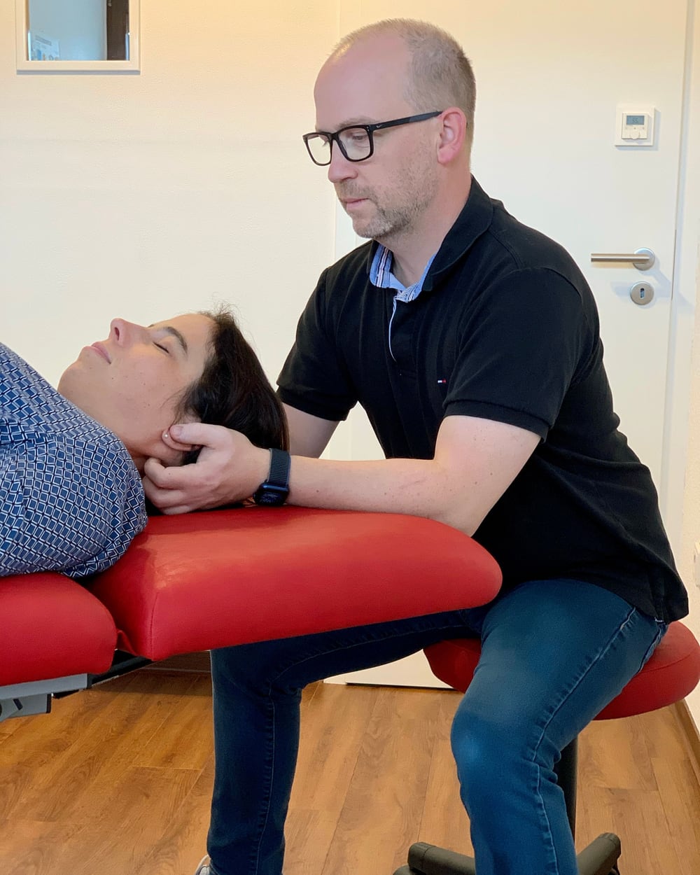 Tobias Kern behandelt eine Patientin auf der Behandlungsliege seiner Praxis